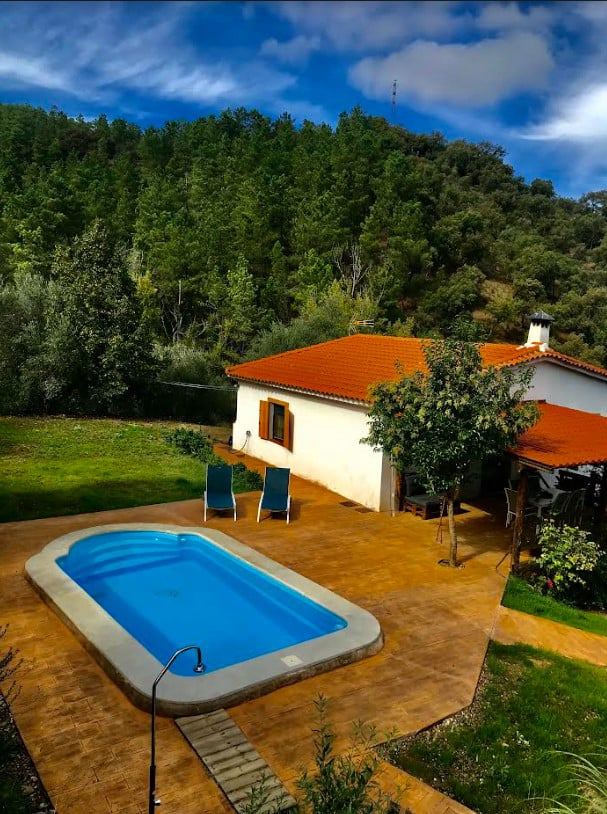 La casa y la piscina privada vistas desde el aire, rodeadas de arbolado