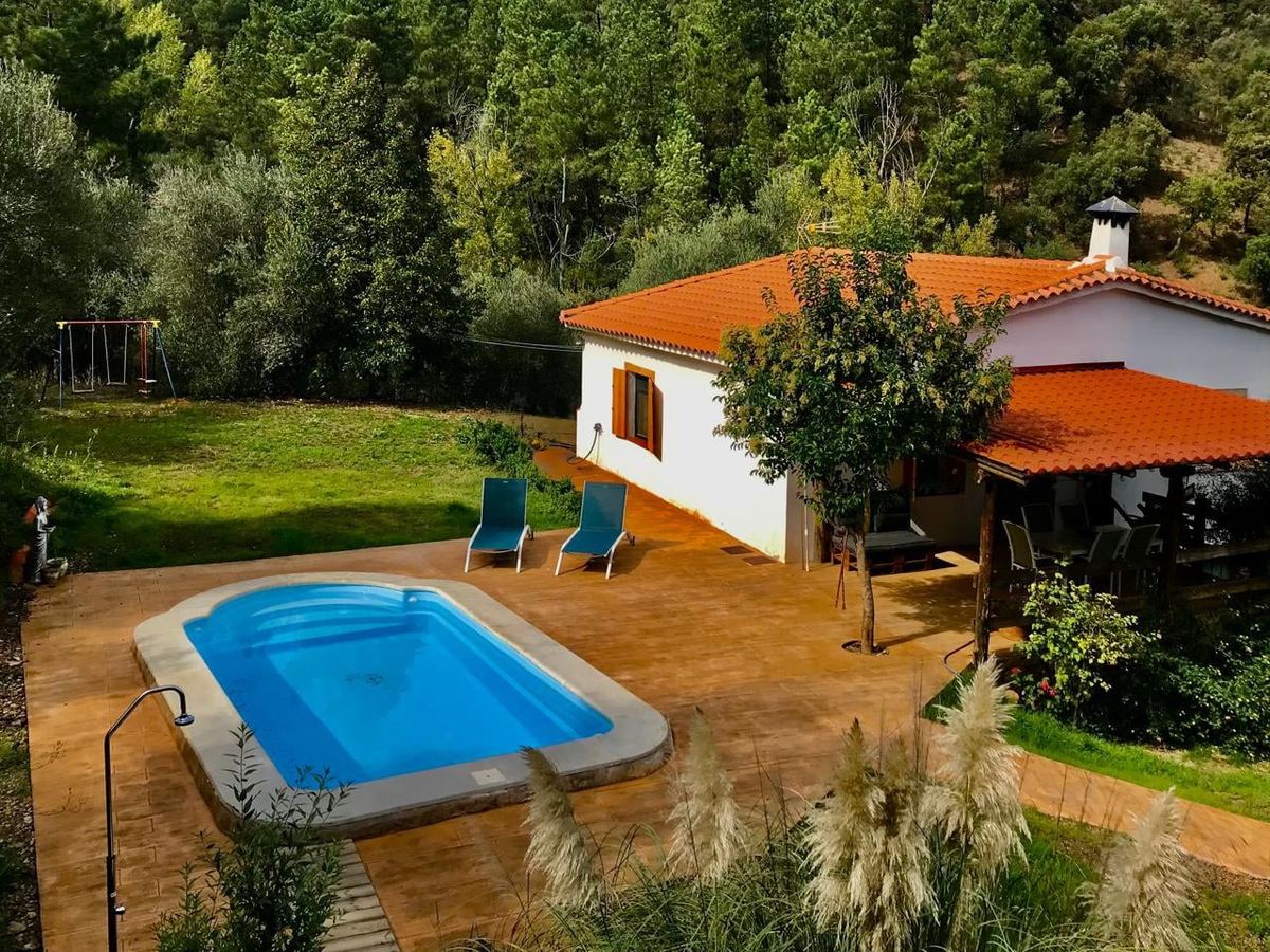 La piscina privada al atardecer, con el jardín y la sierra al fondo